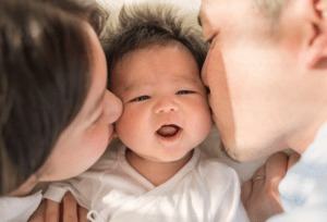 Anya baby & breastfeeding app - Baby being kissed by mum and dad