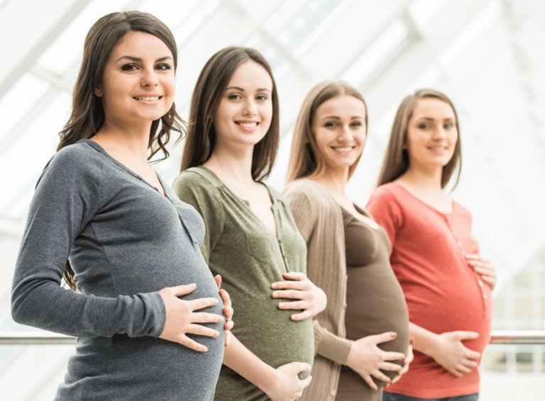 4 pregnant ladies in row wearing different coloured tops