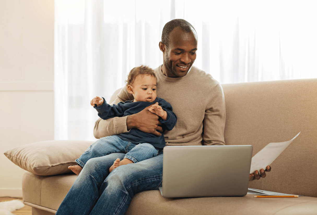 Dad working on his laptop with baby on his lap - Anya pregnancy, baby & breastfeeding app