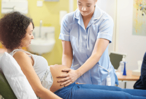 Midwife palpates a pregnant woman's belly at a clinic - Anya baby & breastfeeding app