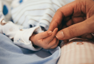 A parent holds a newborn baby's hand - Anya baby & breastfeeding app
