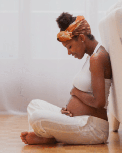 Black mother holds her pregnant belly - Anya baby & breastfeeding app