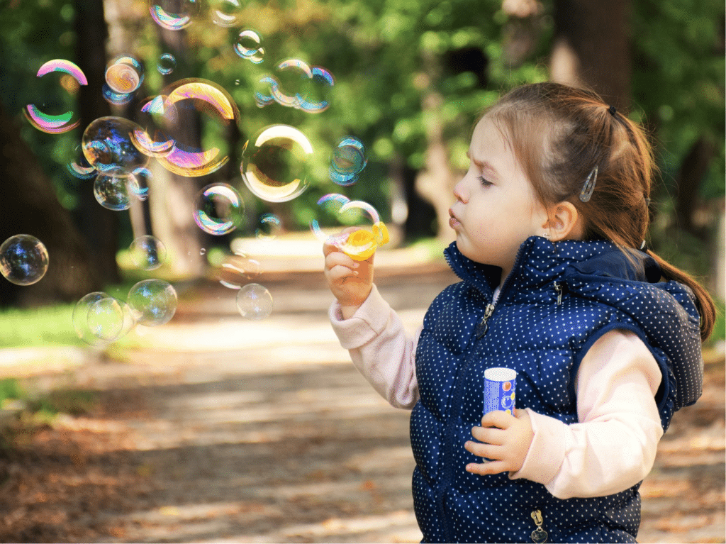 A toddler plays with a bubble blower - Anya baby & breastfeeding app